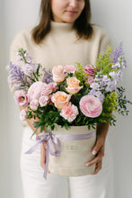 Load image into Gallery viewer, A person holding a beige velvet hat box with a floral arrangement of roses and other foliage, tied with a ribbon.