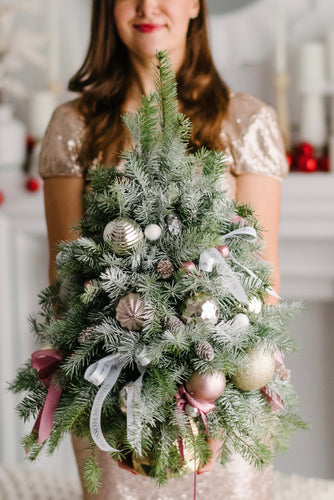 Unique handcrafted miniature tabletop tree adorned with festive ornaments, ribbons, and pastel-colored decorations.